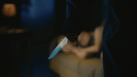 Photo for Horror movie scene. Halloween advertisement concept. Closeup shot girl sleepping on the sofa in the living room, focus on the man maniac standing in fron of her, hand with knife. - Royalty Free Image