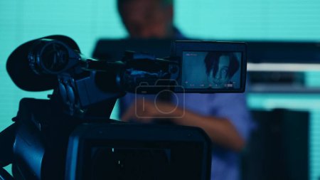 Photo for Close up detail shot of the camera filming, recording the face of a suspect, offender, perpetrator or prisoner talking to a detective, policeman on the background. True crime, documentary, creative. - Royalty Free Image