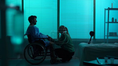 Photo for Full-sized silhouette shot of a disabled man, patient with mobility impairment on a wheelchair, talking happily to a young woman. Positive thinking. Hospital, loved ones, rehabilitation, medical. - Royalty Free Image