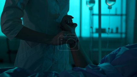 Photo for Close-up detail shot of an unrecognisable woman, nurse, female doctor checking up on her patient laying in a hospital bed. She is checking his heart rate. Hospital, medical service, impatient - Royalty Free Image
