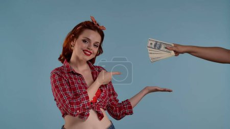 Photo for A young woman walks into the frame. She looks at the camera pointing her finger at the money being handed out to her. She smiles and nods her head. This could be your product here. Medium shot . HDR - Royalty Free Image