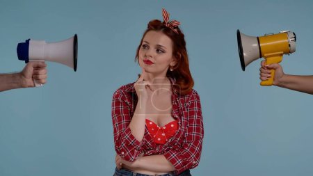 Photo for In the picture on a blue background, a young red-haired woman with bright makeup. Looks to the side and thinks about something, thinks, dreams. Loudspeakers were pointed at her from both sides. HDR - Royalty Free Image
