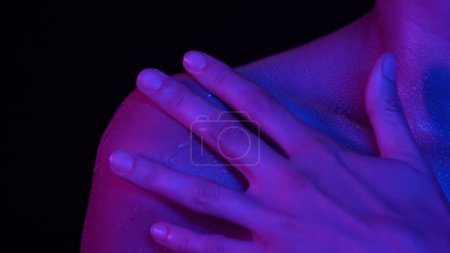 Photo for Skin texture and bodycare creative concept. Portrait of beautiful femalemodel. Closeup studio shot of caucasian woman model body part in neon light, shoulder area touching her skin with water drops. - Royalty Free Image