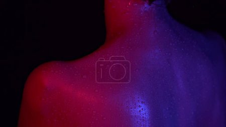 Photo for Skin texture and bodycare beauty concept. Closeup studio shot of beautiful woman body part in neon light, fresh skin with water drops on the back shoulder blades area after shower. - Royalty Free Image