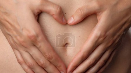 Photo for Skin texture and bodycare healthcare concept. Portrait of female model. Closeup shot of attractive caucasian woman body part, touching tummy area with hands in heart shape, smooth natural skin. - Royalty Free Image