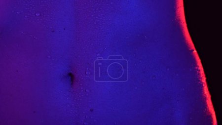 Photo for Skin texture and bodycare healthcare concept. Portrait of attractive young female model. Closeup shot of attractive caucasian woman body part in neon light, belly area smooth skin with water drops. - Royalty Free Image