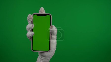 Téléchargez les photos : Détail écran vert isolé chroma clé photo capture momies main tenant un smartphone avec une zone de publicité, espace de travail maquette pour votre clip de promotion ou de publicité. - en image libre de droit