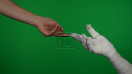 Téléchargez les photos : Détail écran vert isolé chroma photo clé capturant la main des momies atteignant la main humaine, imitant la peinture Michel-Ange. Maquette, espace de travail pour votre clip promotionnel ou publicité. - en image libre de droit