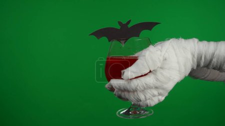 Photo for Detail green screen isolated chroma key photo capturing mummys hand holding a glass of blood, red liquid or sparkling beverage. Mock up, workspace for your promotion clip or advertisement. - Royalty Free Image