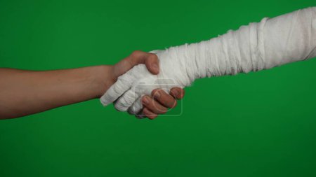 Photo for Detail green screen isolated chroma key photo capturing the mummys hand reaching for the human hand. They are shaking their hands friendly. Mock up, workspace for your promotion clip or advertisement - Royalty Free Image