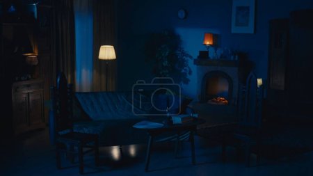 Photo for Shot of a flat, an apartment in the night. Muffled, low light from multiple lamps in a room. Couch, sofa, fireplace and other furniture in the room. Late night, after midnight. Dark, ominous. - Royalty Free Image
