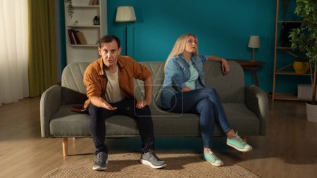 Photo for A visit to a family psychologist for a married couple. A man talks indignantly about problems in his relationship while sitting next to a woman who ignores him. Crisis of relationships in family life - Royalty Free Image