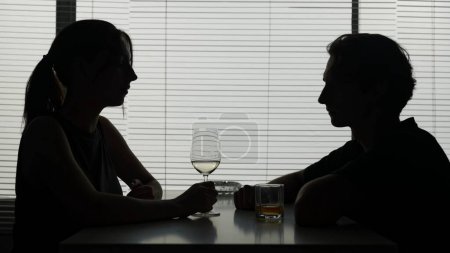 Photo for In a shot a young woman and man are at a table. They talk that about what, converse, after they drink an alcohol continuing to converse. Alcoholism, dependence, dialog. Medium shot. - Royalty Free Image