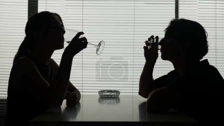 Photo for In a shot a young woman and man are at a table. They talk that about what, converse, after they drink an alcohol continuing to converse. Alcoholism, dependence, dialog. Medium shot. - Royalty Free Image