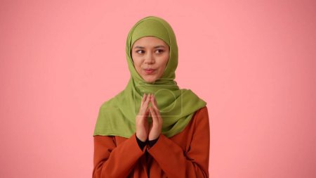 Photo for Medium-sized isolated photo capturing an attractive young woman wearing a hijab, veil. She is looking to the sides sneakily, as if she has a plan. Place for your advertisement, cultural, diversity. - Royalty Free Image
