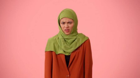 Photo for Medium-sized isolated photo capturing an attractive young woman wearing a hijab, veil. She is wincing at the camera in disgust and dislike. Place for your advertisement, cultural, diversity. - Royalty Free Image