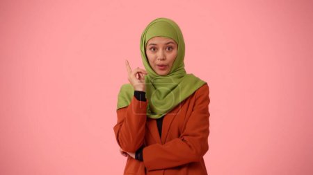 Photo for Medium-sized isolated photo capturing an attractive young woman wearing a hijab, veil. She raised her finger in the air as if she came up with an idea. Place for your advertisement, cultural diversity - Royalty Free Image
