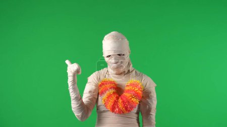 Téléchargez les photos : Écran vert isolé chroma photo clé capturant une momie portant un lei, collier de fleurs hawaïennes, vous appelant à rejoindre, pointant derrière. Maquette, espace de travail pour votre clip promotionnel ou publicité. - en image libre de droit