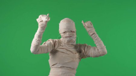 Téléchargez les photos : Écran vert isolé chroma photo clé capturant une momie secouant les bras, dansant sur de la musique, heureux et détendu. Vacances d'Halloween. Maquette, espace de travail pour votre clip promotionnel ou publicité. - en image libre de droit