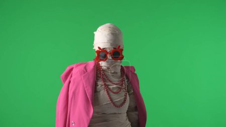 Foto de Pantalla verde aislada croma clave de la foto la captura de una momia con chaqueta rosa, collar y gafas de actuar elegante y elegante. Prepárate, espacio de trabajo para tu clip de promoción o anuncio. - Imagen libre de derechos