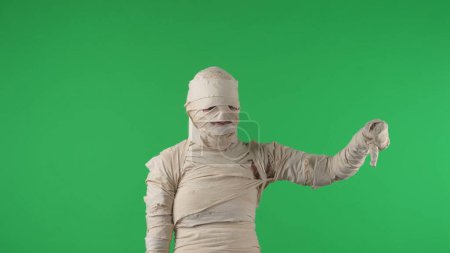Photo for Green screen isolated chroma key photo capturing a mummy staring at the cameta and giving a thumbs down. Halloween holidays. Mock up, workspace for your promotion clip or product advertisement. - Royalty Free Image