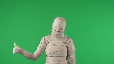 Photo for Green screen isolated chroma key photo capturing a mummy showing something with its hand and giving a thumbs up. Halloween holidays. Mock up, workspace for your promotion clip or product advertisement - Royalty Free Image