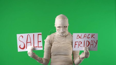Photo for Green screen isolated chroma key photo capturing a mummy holding two pieces of paper with sale and black friday written on them in capitals. Mock up for your promotion clip or product - Royalty Free Image