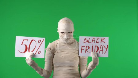 Photo for Green screen isolated chroma key photo capturing a mummy holding two pieces of paper with 50 percent and black friday written on them. Mock up for your promotion clip or product advertisement. - Royalty Free Image