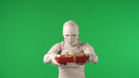 Photo for Green screen isolated chroma key photo capturing a mummy offering, giving a present, gift to the camera. Halloween holidays. Mock up, workspace for your promotion clip or advertisement. - Royalty Free Image