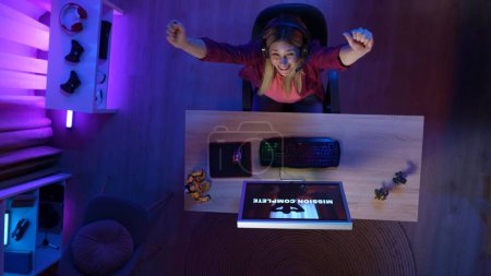 Photo for Gaming and streaming advertisement concept. Person on the PC at home. Top view of woman at the computer, won the mission in the game, looking up holding hands victory gesture. - Royalty Free Image