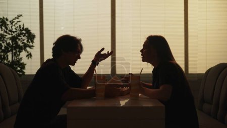 Photo for Everyday life and people relationships concept. Portrait of couple in cafeteria. Silhouette of man and girl sitting at the bistro bar talking, arguing, angry face expression tense conversation. - Royalty Free Image