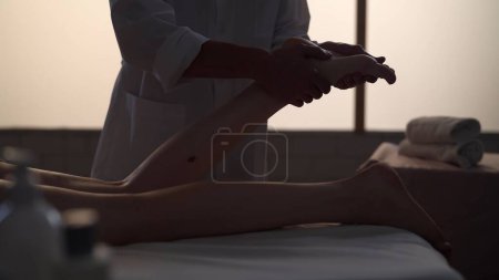 Téléchargez les photos : Un tir moyen. Masseur, spécialiste du massage donnant un massage des pieds à son patient. Silhouettes d'une femme et d'un homme dans la salle de massage, procédure spa. Soins de santé, traitement médical, thérapie holistique. - en image libre de droit
