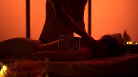 Téléchargez les photos : Masseur, spécialiste du massage redonnant massage à son patient. Silhouettes dans la salle de massage, procédure spa. Des néons exotiques, orange. Soins de santé, traitement médical, thérapie holistique. - en image libre de droit