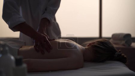 Téléchargez les photos : Un tir moyen. Masseur, spécialiste du massage redonnant massage à son patient. Silhouettes d'une femme et d'un homme dans la salle de massage, procédure spa. Soins de santé, traitement médical, thérapie holistique. - en image libre de droit