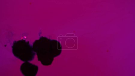 Photo for Water and different liquid creative advertising concept. Close up studio shot of aqua surface. Dark ink mixing in vibrant colored purple water creating stains, abstract background wallpaper. - Royalty Free Image