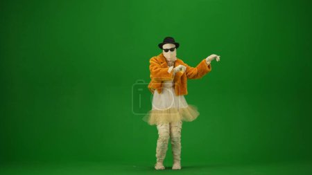 Photo for Glamorous mummy dances in an orange fur coat, hat and sunglasses. Green screen isolated chroma key. Mock up, workspace, advertisement. Full length. Halloween holidays. - Royalty Free Image