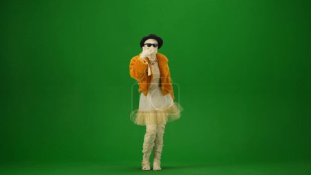 Téléchargez les photos : Momie glamour en manteau de fourrure orange, chapeau et lunettes de soleil envoie un baiser d'air. Écran vert isolé clé chromatique. Maquette, espace de travail, publicité. Sur toute la longueur. Vacances d'Halloween. - en image libre de droit