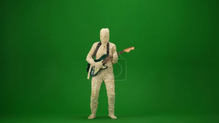Foto de Pantalla verde aislada croma clave foto captura de una momia tocando la guitarra y bailando con la música. Vacaciones de Halloween. Prepárate para tu clip de promoción o anuncio. Longitud completa. - Imagen libre de derechos