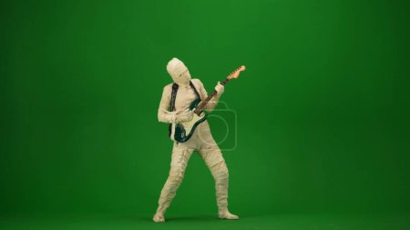Téléchargez les photos : Écran vert isolé chroma photo clé capturant une momie jouer de la guitare et danser sur la musique. Vacances d'Halloween. Maquette pour votre clip de promotion ou publicité. Longueur totale. - en image libre de droit