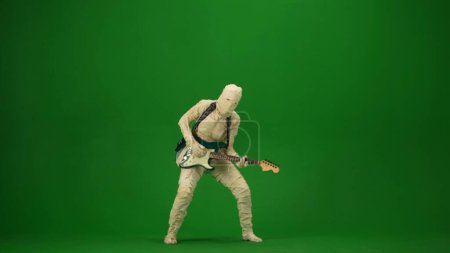 Photo for Green screen isolated chroma key photo capturing a mummy playing guitar and dancing to the music. Halloween holidays. Mock up for your promotion clip or advertisement. Full length. - Royalty Free Image