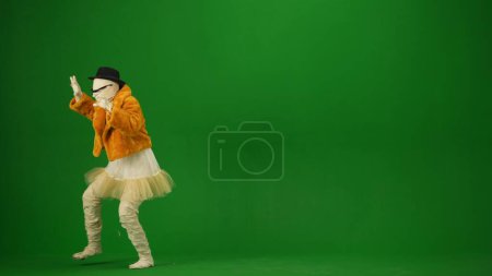 Foto de Glamorosa momia posando en un abrigo de piel naranja, sombrero y gafas de sol. Tecla de croma aislada de pantalla verde. Mock up, espacio de trabajo, publicidad. Longitud total. Media vuelta. Halloween vacaciones. - Imagen libre de derechos