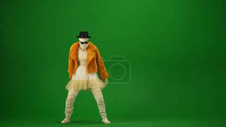 Photo for Glamorous mummy posing in an orange fur coat, hat and sunglasses. Green screen isolated chroma key. Mock up, workspace, advertisement. Full length. Halloween holidays. - Royalty Free Image