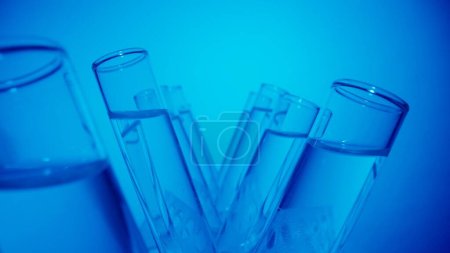 Photo for Close up video neon blue light test tubes filled with fuild in a laboratory. Scientific experiment, research, study. Detail shot of lab glassware. Creative content or medical advertisement. - Royalty Free Image
