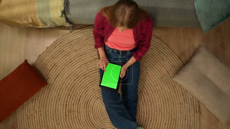Foto de Vista superior de la captura de una mujer joven sentada en el suelo, mirando a la pantalla de la tableta con un área de publicidad, el espacio de trabajo se burlan de ella. Ocio, compras online, redes sociales y comunicación. - Imagen libre de derechos