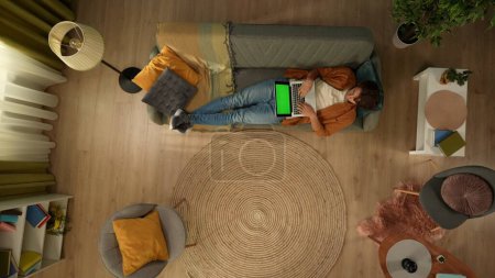 Foto de Vista superior de la captura de un joven acostado en el sofá, mirando a la pantalla del ordenador portátil con un área de publicidad, el espacio de trabajo se burlan de él. Ocio, compras online, redes sociales y comunicación. - Imagen libre de derechos