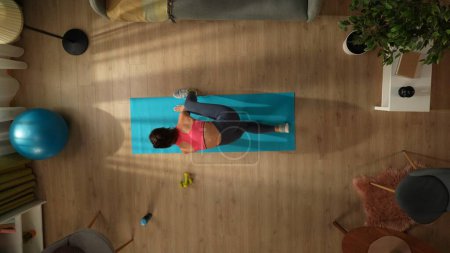 Photo for Top view capturing a young woman doing her morning yoga exercise, stretching in front on the window. Home, room, indoor activities. Healthy and active lifestyle, morning routine, achieving the goals. - Royalty Free Image