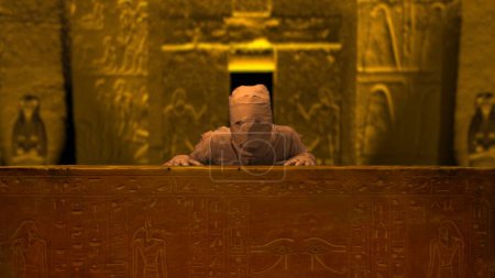 Foto de Enterramiento del faraón egipcio. La momia resucitando, levantándose detrás del sarcófago, ataúd, mirando a la cámara. De tamaño medio. Clip de promoción o anuncio de Halloween. - Imagen libre de derechos