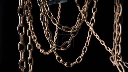 Macro shot of a rusty old metal chain on a black background. The chain links are covered in rust and dirt. Old hanging chain