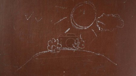 Photo for Textured brown chalkboard background. Landscape with sun, clouds and flowers is sketched on the board with a piece of white chalk in close up. Educational and creative content, schooling concept. - Royalty Free Image
