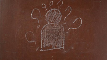 Téléchargez les photos : Fond de tableau brun texturé. Figure humaine abstraite avec des points d'interrogation autour dessinés sur la planche avec un morceau de craie en gros plan. Contenu éducatif et créatif, concept scolaire. - en image libre de droit